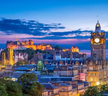 View of the Edinburgh skyline at dusk, with clock tower and castle in the distance